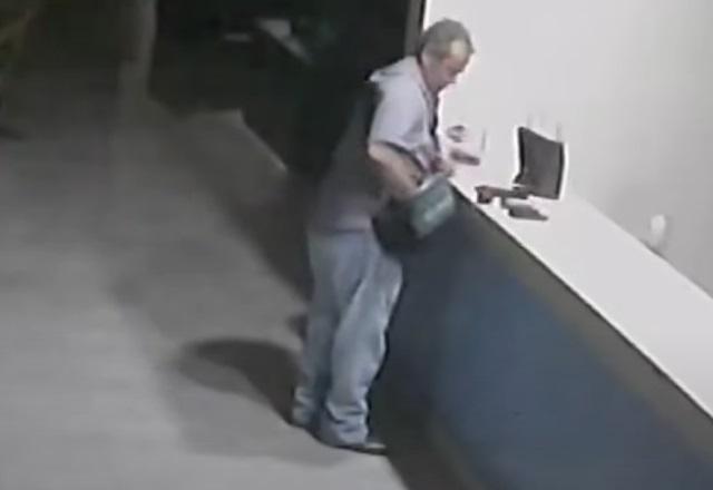 Homem branco no balcão de hotel, com arma em cima do móvel