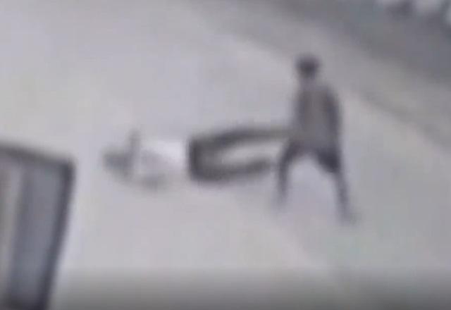 Homem caído no chão de rua enquanto outro, de pé, se prepara para agredi-lo