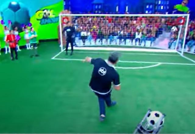 Homem chutando uma bola em direção ao gol em um programa de televisão