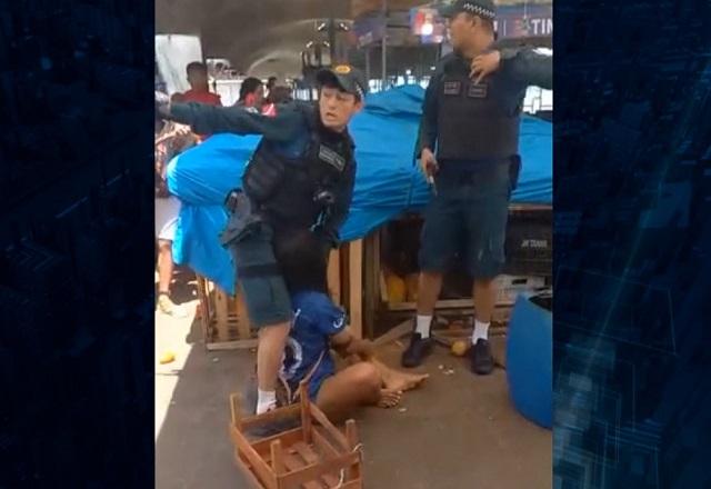 Homem com farda de policial agredindo mulher caída no chão