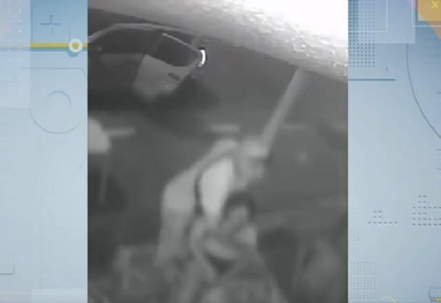Homem de camiseta branca roubando pertences de vítimas em frente a lanchonete