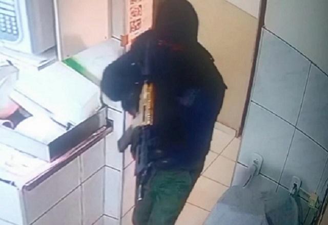 Homem encapuzado e fortemente armado durante ação criminosa flagrada por câmera de segurança