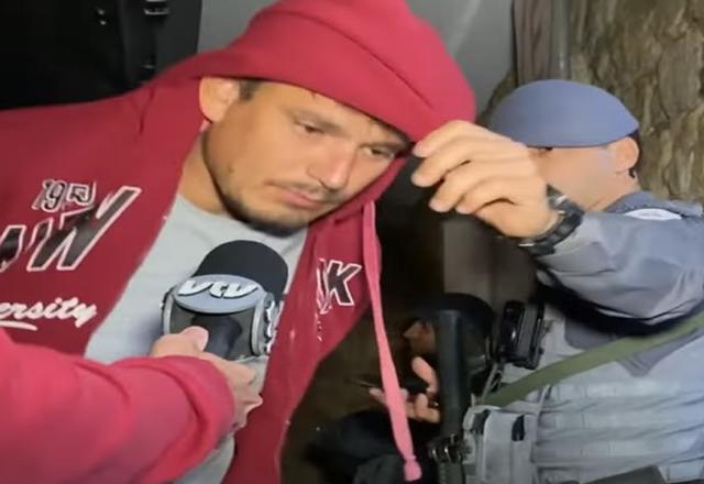 Homem encapuzado sai de viatura policial