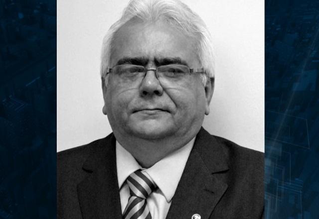 Homem idoso branco, de cabelos brancos. óculos de grau e terno preto, em foto em preto e branco