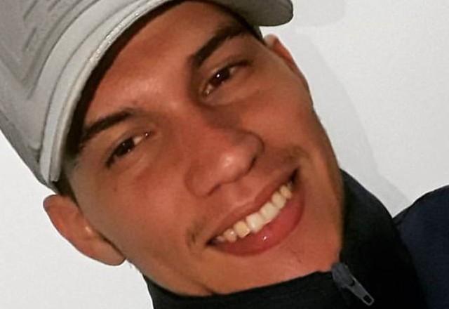Homem jovem sorrindo, de boné cinza e casaco preto