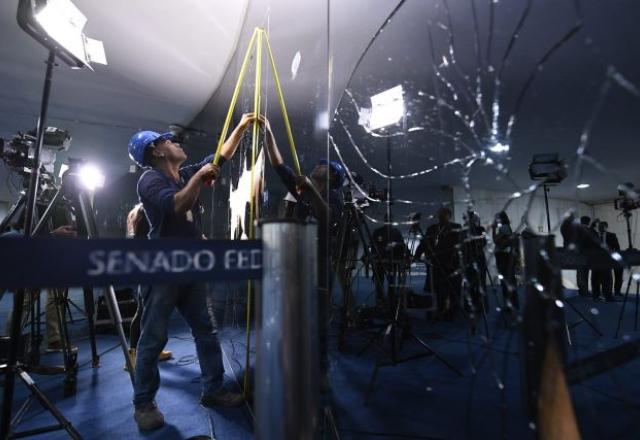 Homem mede vidros do Congresso depois dos estragos do dia 8 de janeiro