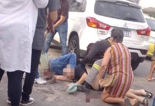 Homem morto no chão ao lado de carro branco e pessoas ao redor