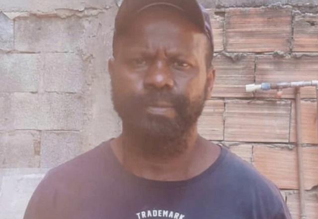 Homem negro, de barba, boné e camiseta azul escuro