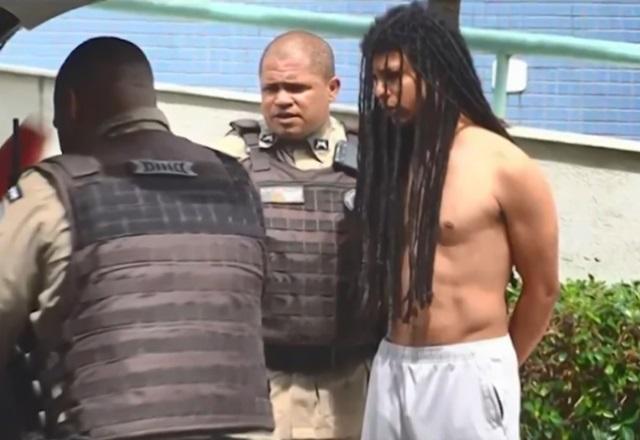 Homem negro, de tranças e dread e sem camisa, sendo preso por policiais militares fardados