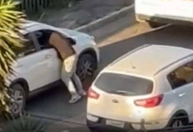 Homem pendurado em janela de veículo parado