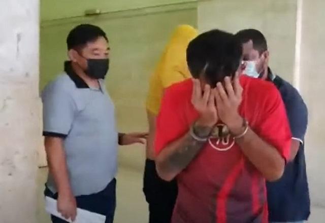 Homens de camiseta vermelha e amarela, um deles algemado, sendo presos por dois policiais