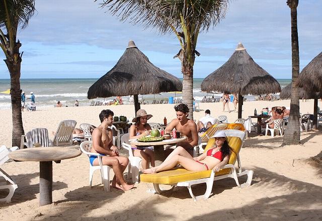 Homens e mulheres sentado a mesa de quiosque em praia