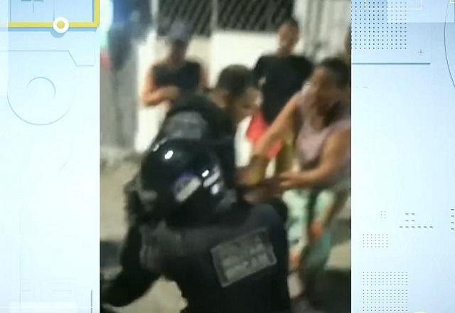 Homens fardados de policiais durante pancadaria no meio da rua, durante a noite, com mulher de roupa roxa tentando intervir