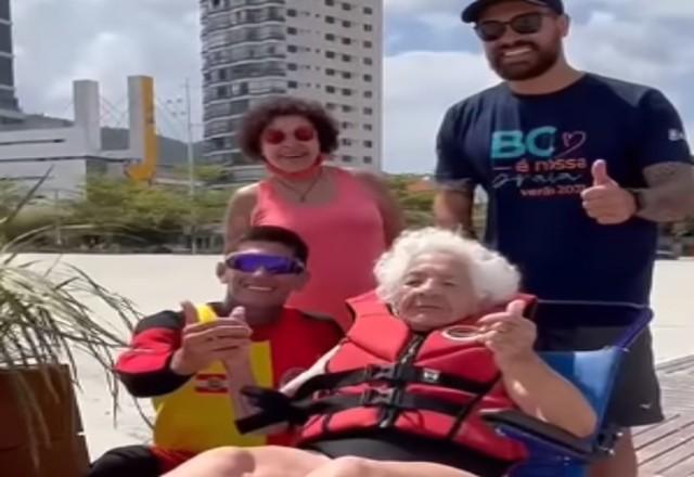 Idosa em cadeira de rodas e acompanhantes a caminho do mar