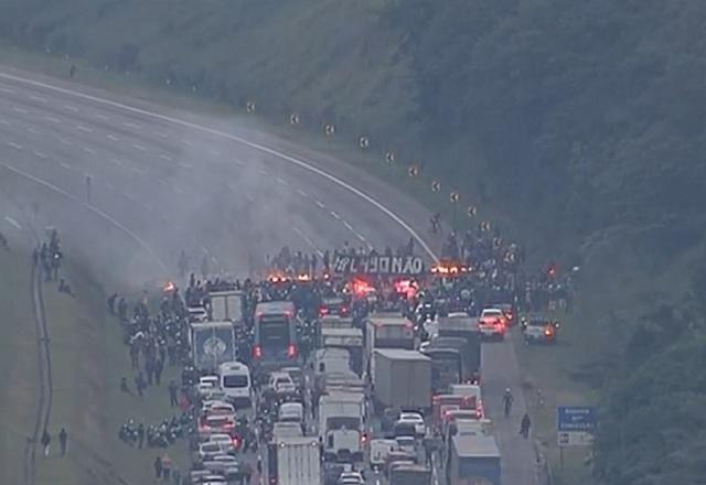 Imagem aérea de protesto em rodovia, com faixas interditadas