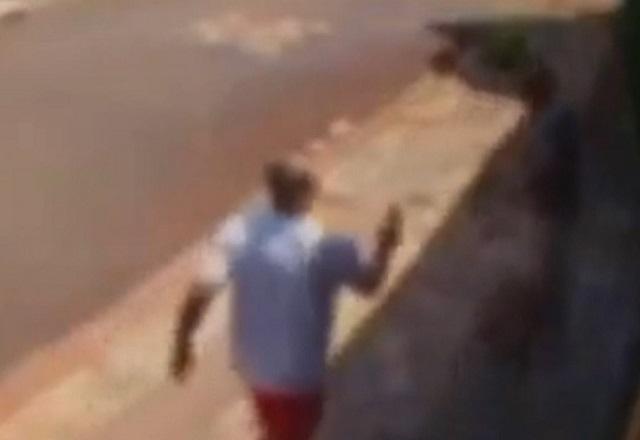Imagem de câmera de segurança desfocada mostrando discussão entre vizinhos armados com arma e espada