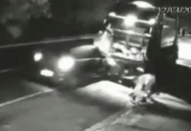 Imagem de câmera de segurança em preto e branco com carro colidindo com traseira de caminhão de lixo