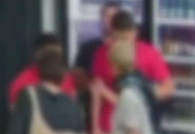 Imagem desfocada de duas mulheres discutindo com dois homens em frente a geladeiras de bebidas