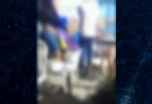 Imagem desfocada de local de massacre, com pessoas em pé em meio a bagunça e feridos no chão