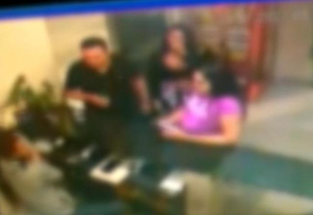 Imagem desfocada de recepção de hotel, com homem de camiseta preta e duas mulheres