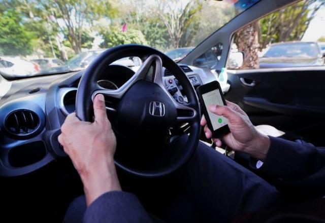 Imagem do interior de um veículo com um motorista ao telefone