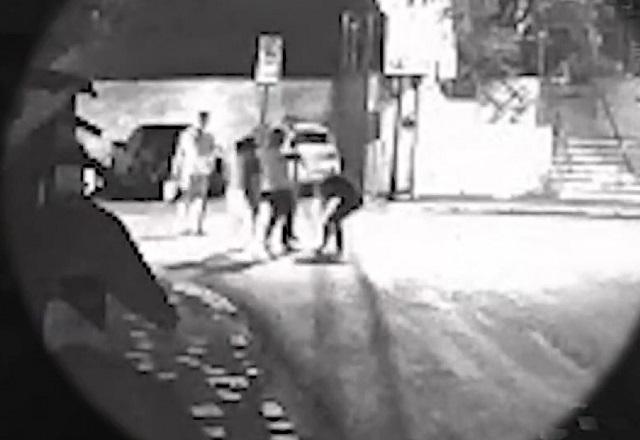 Imagem em preto e branco de pessoas durante confusão e briga no meio da rua