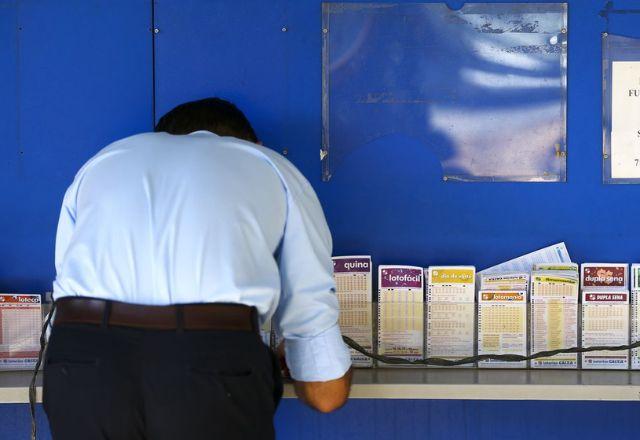 Imagem mostra apostador de costas aaixado em balcão preenchendo cartela