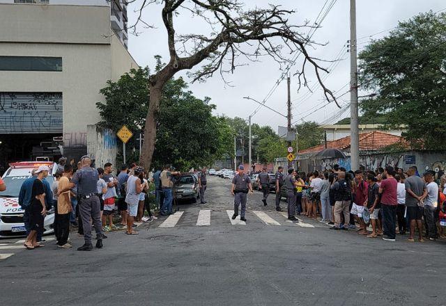 Imagem mostra pessoas e viaturas de polícia além da movimentação na rua onde fica a escola onde aconteceu o ataque do aluno com uma faca que feriu quatro pessoas e matou uma