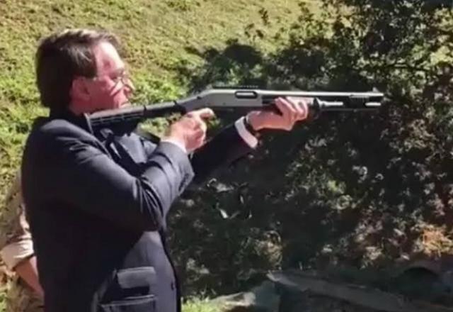 Jair Bolsonaro segurando arma