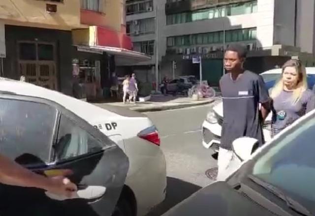 Jovem negro sendo conduzido para viatura por policial loira