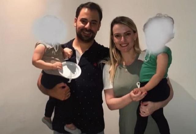 Leandro Ceschini e Érica Ceschini posam para foto segurando os dois filhos pequenos, que estão com os rostos desfocados para não serem identificados