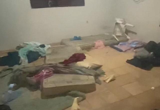 Local bagunçado, com colchão, cadeira e roupas espalhadas em cômodo de imóvel