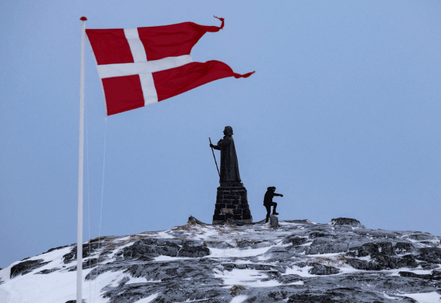 Homem perto da bandeira de Dinamarca em Nuuk, na Groenlândia | Foto: Marko Djurica/Reuters - 09.03.2025