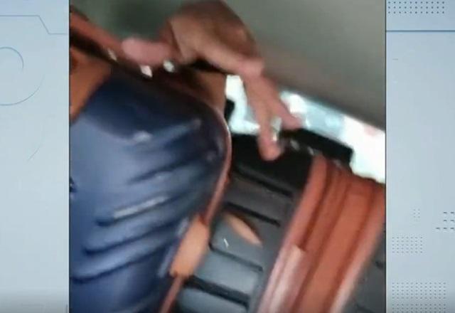 Mão de homem sobre malas de viagem acomodadas em banco traseiro de veículo