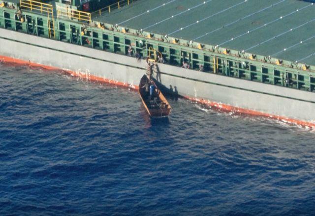 Migrantes que sobreviveram a naufrágio sobem em navio de carga na costa italiana