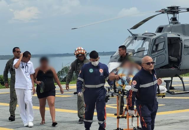 Militares levam pescadora resgatada em maca após realizar operação de salvamento