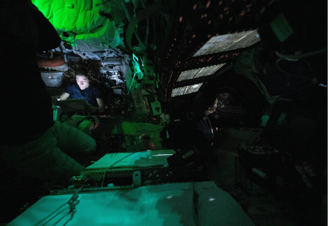 Christina Koch lê em tablet enquanto Jeremy Hansen observa o espaço na cápsula Orion | Divulgação/Nasa