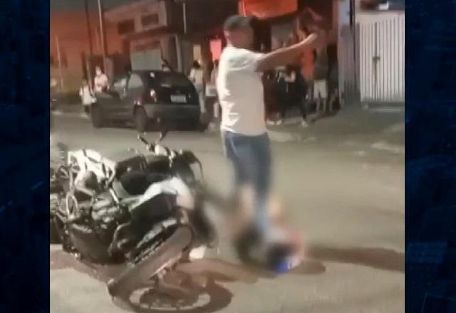 Motocicleta deitada no asfalto, com criminoso baleado ao lado e com imagem desfocada para não ser identificado