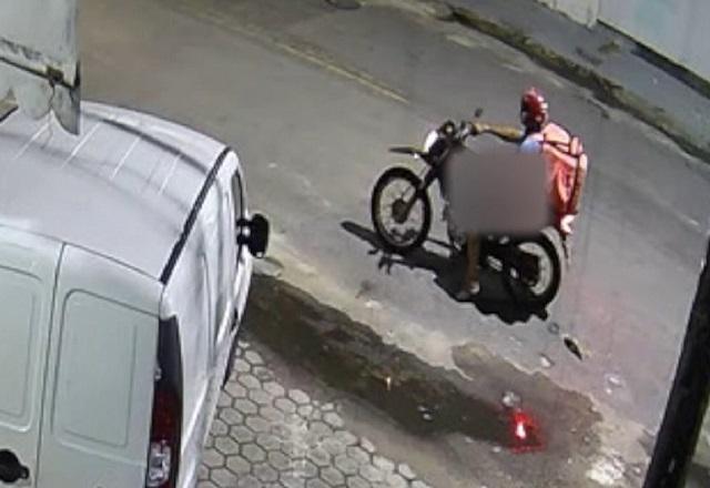 Motociclista com mochila térmica, a bordo de moto no meio da rua, com imagem desfocada na região íntima