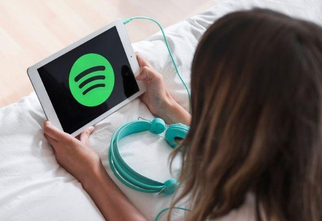 Mulher acessa o Spotify por meio de um tablet