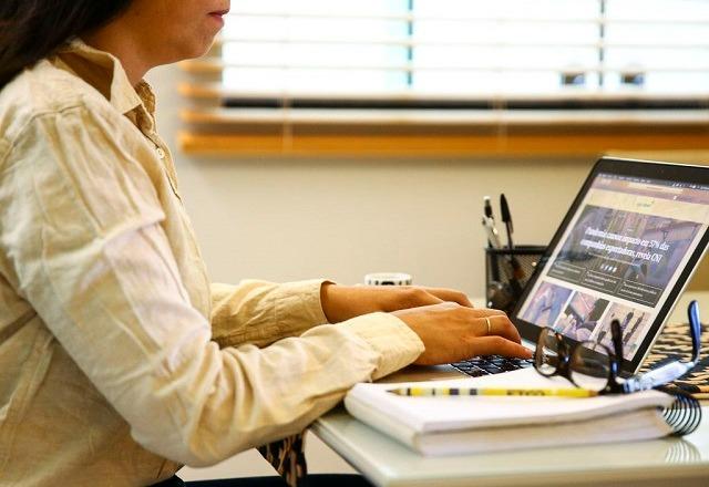 Mulher atende ao telefone enquanto digita no computador