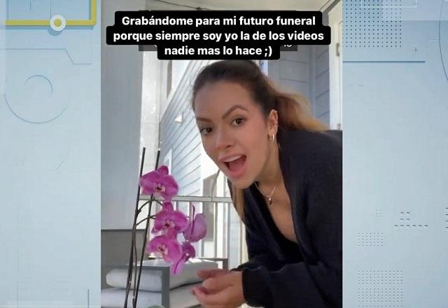 Mulher branca com cara de espanto ao lado de vaso de flores