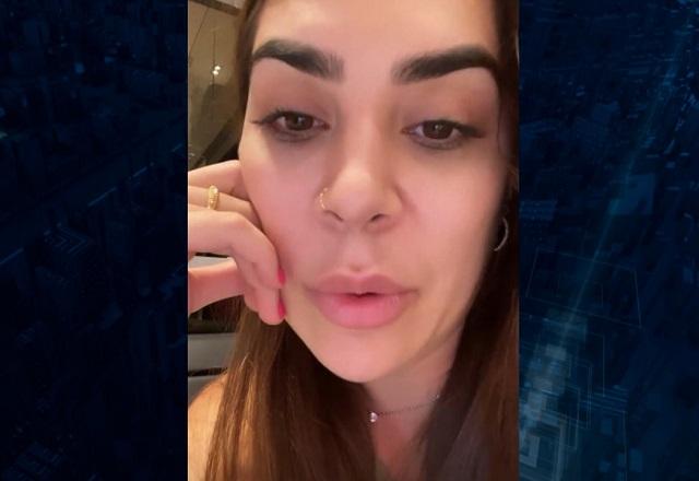 Mulher branca, de cabelos escuros, enquanto grava vídeo com a câmera frontal do celular
