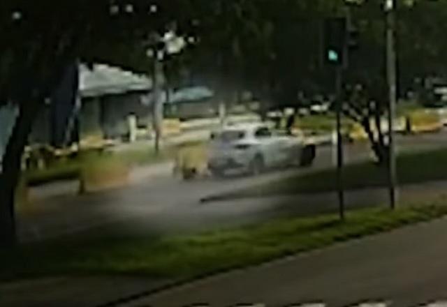 Mulher caindo no asfalto após ser arrastada por carro em avenida, durante o dia