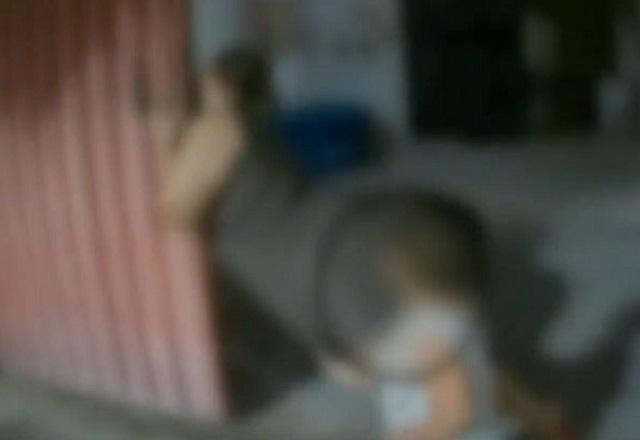 Mulher de roupa preta desmaiando e se segurando em portão de residência