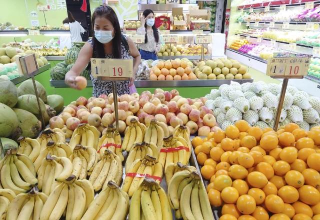 Mulher escolhe frutas em supermercado