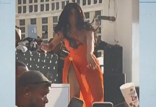 Mulher negra, de vestido, durante show, arremessando microfone em direção à plateia