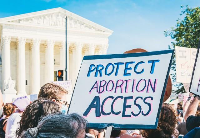 Mulher segura cartaz que pede pela proteção dos direitos ao acesso a aborto