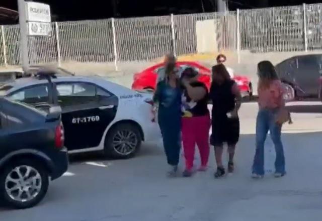 Mulher sendo presa, acompanhada de outras pessoas, durante o dia