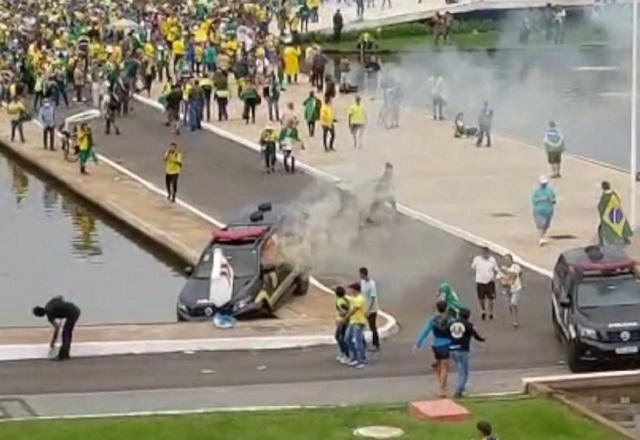 Multisão em torno de espelho dágua, com viaturas policiais danificadas